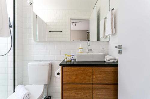 ein weißes Bad mit einem Waschbecken und einem WC in der Unterkunft Predio com apartamentos completos, com piscina e a passos da praia - Agua Marinha in Florianópolis