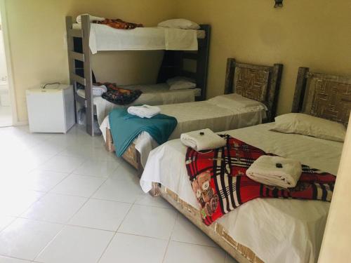 a room with three bunk beds and a tiled floor at Hotel Fazenda VCP in Silva Jardim