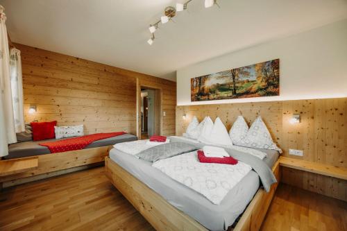 two beds in a room with wooden walls at Bauernhof Unterbichl in Flachau