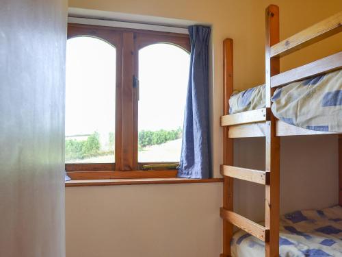 a bedroom with bunk beds and a window at Merlin View in Saint Mawgan