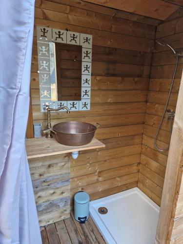 ein Holzbadezimmer mit einem Waschbecken und einer Badewanne in der Unterkunft Les cabanes féeriques du Cheix in Saint-Diéry