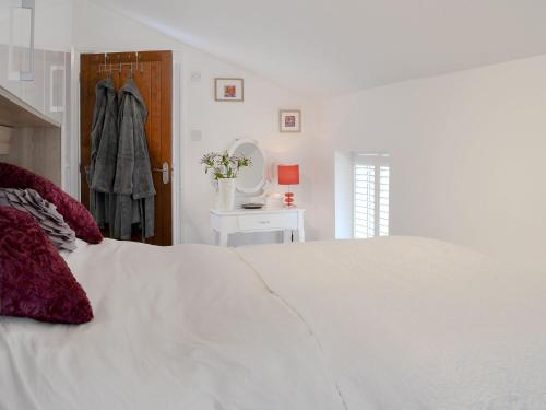 a white bedroom with a large white bed and a table at The Shoe Box in Northam