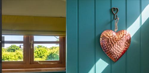 a heart hanging on a wall next to a window at Shepherds Hut with Scandinavian Hot Tub and hydromassager in Sway