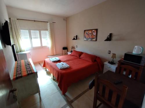 1 dormitorio con cama roja y ventana en ENTRESIERRAS Y RIO en Santa Rosa de Calamuchita