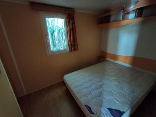 Limogne-en-QuercyCAMPING LE BEL AIR mobil home LE CORNOUILLER 4 personnes的一间有床和窗户的小卧室