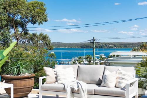 un divano su un patio con vista sull'acqua di Huge Bayside Luxury Resort-Style Home with Pool a Burraneer
