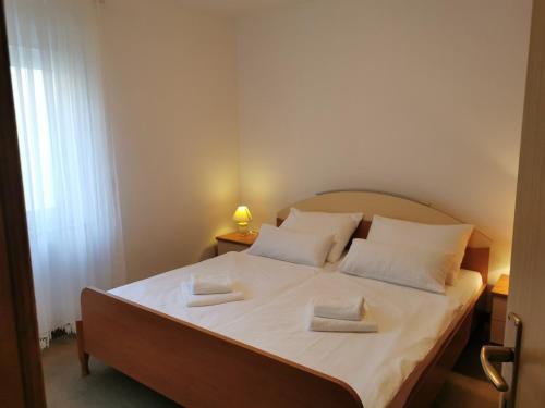 a bedroom with a bed with white sheets and pillows at Apartments Dajana Silo in Šilo