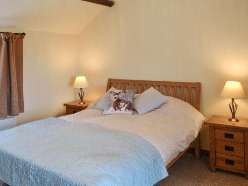 a bedroom with a bed with two tables and two lamps at Brodie Cottage in Aspatria