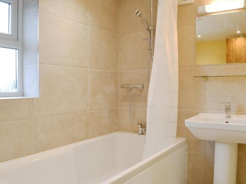 a bathroom with a bath tub and a sink at Brodie Cottage in Aspatria