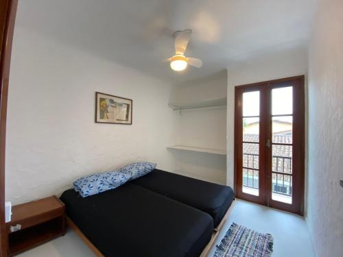 a living room with a black couch and a window at Casa com Spa Praia do Pernambuco in Guarujá