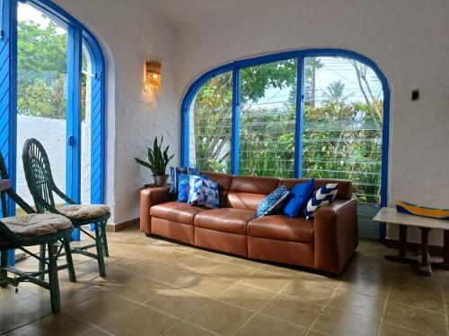a brown leather couch in a room with large windows at Casa com Spa Praia do Pernambuco in Guarujá