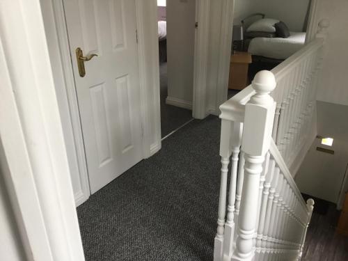 um corredor com uma porta branca e um estojo de escadas em Glenview Self Catering Holiday Home em Portrush