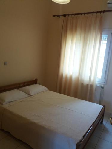 1 dormitorio con 1 cama grande y ventana en Irini's Appartment 2, en Néa Koútali