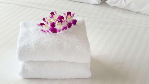 a white towel with a purple flower on a bed at Studios & Suites 4 Less Charlotte in Charlotte