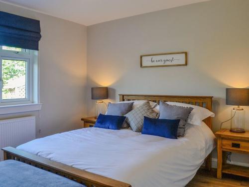 a bedroom with a large white bed with blue pillows at Culbae Cottage in Whauphill