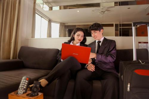 um homem e uma mulher sentados num sofá com um portátil em Hotel America Chiclayo em Chiclayo