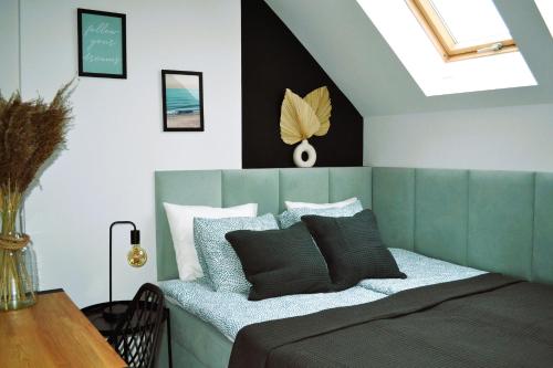 a bedroom with a bed with a green head board at Norda Loft in Dębki