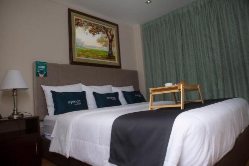 um quarto com uma cama grande e almofadas azuis e brancas em Hotel America Chiclayo em Chiclayo