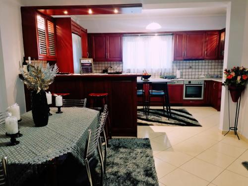 a kitchen with red cabinets and a table with a table cloth at Thira Apartment near Athens Airport in Spáta