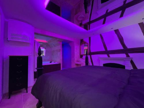Un dormitorio con una cama con luces moradas. en Le Jacuzzi en Rouen