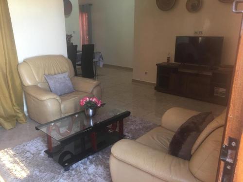 ein Wohnzimmer mit 2 Stühlen und einem TV in der Unterkunft Villa chez Julien in Rufisque
