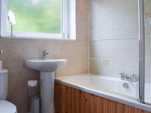 a bathroom with a sink and a tub and a toilet at Treetops in Bowness-on-Windermere
