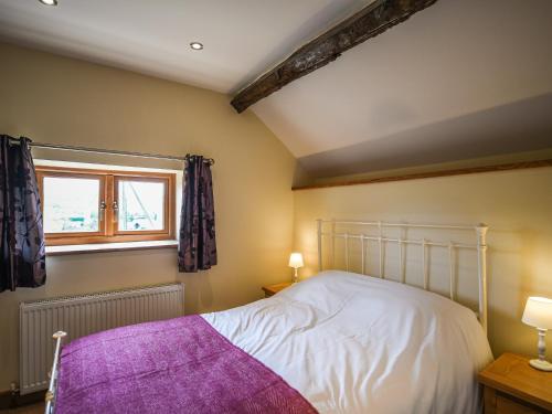 a bedroom with a white bed and a window at Pentre Cottage in Meifod