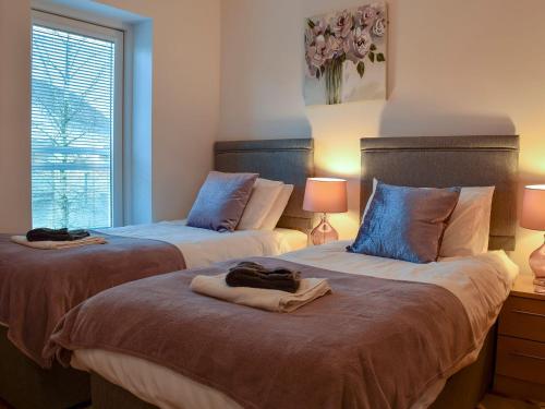 1 Schlafzimmer mit 2 Betten, 2 Lampen und einem Fenster in der Unterkunft Chestnut Lodge in Somerford Keynes