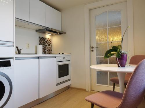 une cuisine avec des placards blancs et une table avec des chaises dans l'établissement Elite Residence, à Timişoara