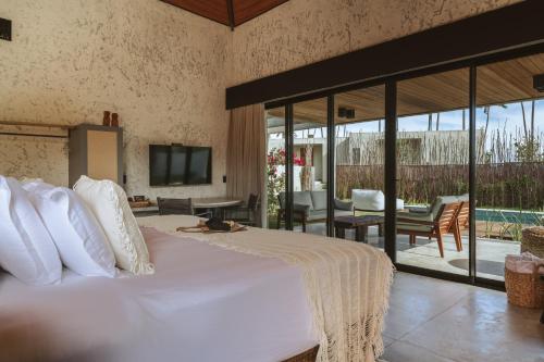 a bedroom with a large white bed and a patio at Tuju Boutique Hotel in Passo de Camarajibe