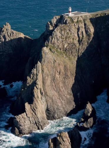 a rock cliff with a lighthouse on top of it at Acogedor piso en Cariño in Cariño