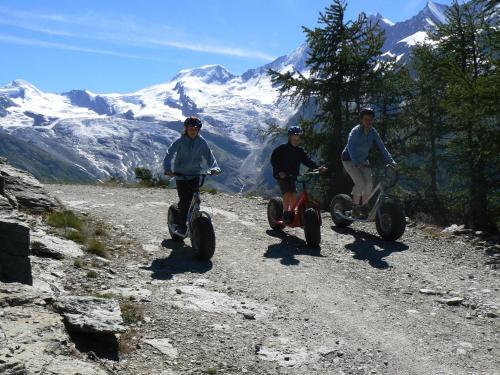 three people riding on scooters on a mountain road at Chalet Stadel in Saas-Grund