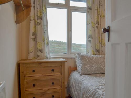 um quarto com uma cama, uma cómoda e uma janela em Avoca em Looe