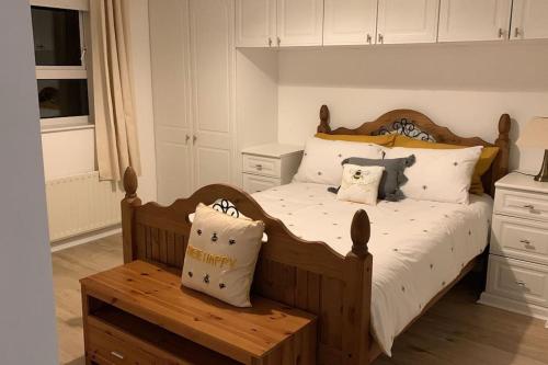 1 dormitorio con cama de madera con almohadas y banco en Bumblebee Cottage, en Donegal