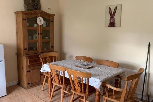 una sala da pranzo con tavolo, sedie e frigorifero di Bumblebee Cottage a Donegal