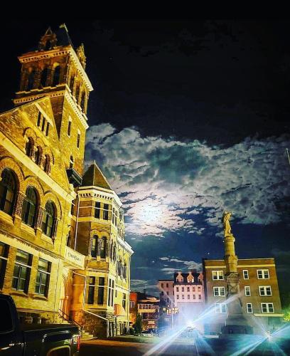 City Hall Grand Hotel في ويليامزبورت: مدينة في الليل مع برج الساعة والمباني