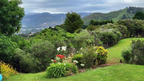 a garden with flowers and trees and mountains in the background at Boutique Art Retreat in Upper Hutt