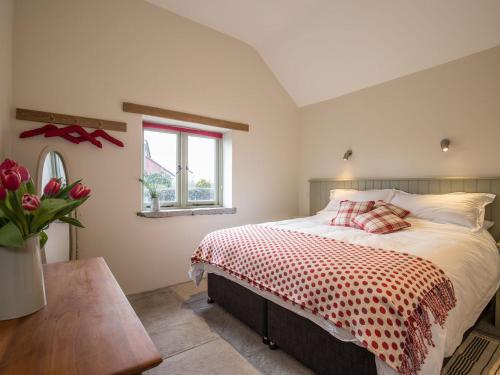 a bedroom with a bed with a red and white comforter at Square Barn - Ukc2869 in Baltonsborough