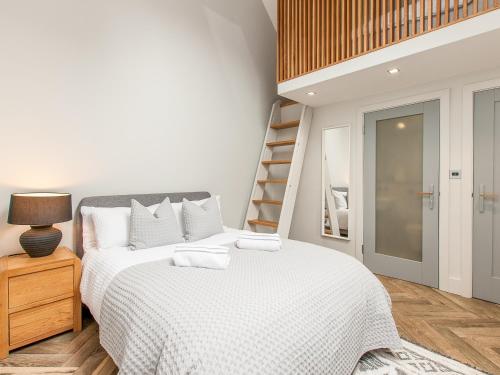 a white bedroom with a bed and a ladder at Home Barn in Lyminge