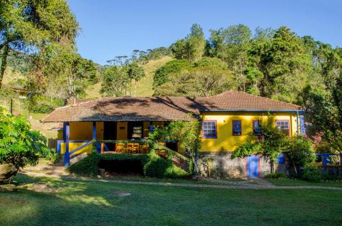 a yellow house with a hill in the background at Hospedaria Fazenda São João do Vale da Grama in Visconde De Maua