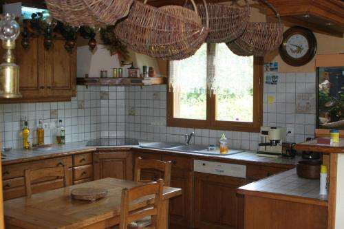 cocina con armarios de madera, mesa y ventana en Chambre d'hôtes "LES CRETS" en Mercury