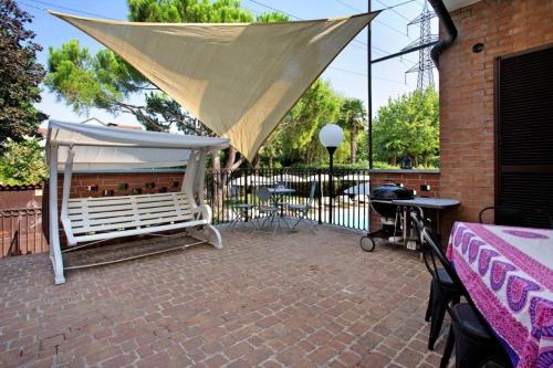 eine Terrasse mit einem weißen Baldachin, einem Tisch und einem Grill in der Unterkunft Villa La palmetta in Peschiera Borromeo