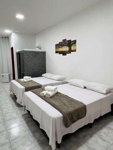 three beds in a room with white walls at Pousada Styllus da Serra in Miguel Pereira