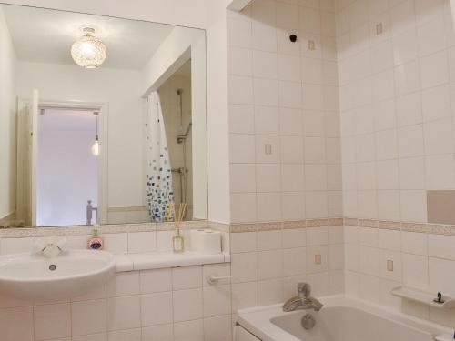 a bathroom with a sink and a tub and a mirror at Carlton House in Hazel Grove