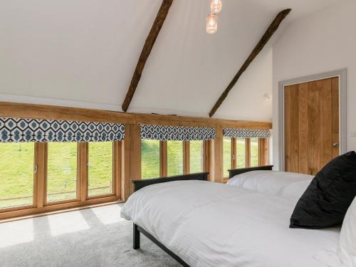 two beds in a room with windows at East Dunster Deer Farm Linny in Cadeleigh