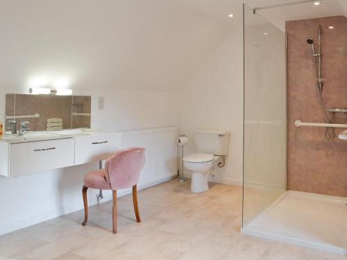 a bathroom with a pink chair and a sink and a shower at The Coach House in Alford