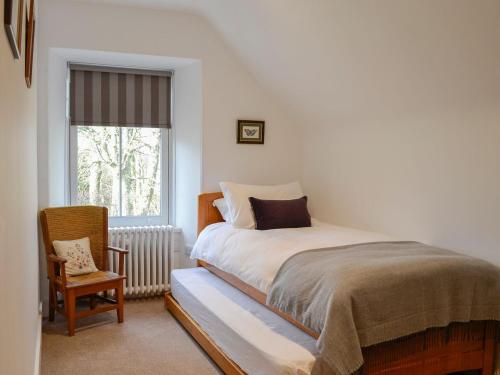 a bedroom with a bed and a chair and a window at The Coach House in Alford