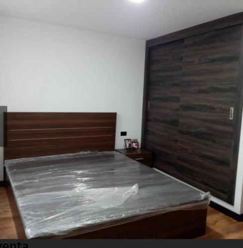 1 dormitorio con 1 cama y puerta de madera grande en Xiomara1, en Quito