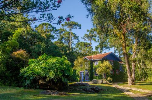 a house in the middle of a yard with trees at Hospedaria Fazenda São João do Vale da Grama in Visconde De Maua