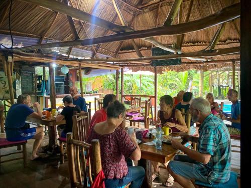 un grupo de personas sentadas en mesas en un restaurante en Casa de la Iguana, en Lívingston